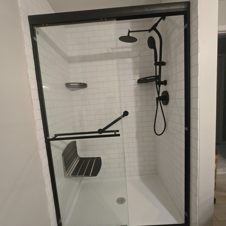 Accessible modern shower with dual showerheads, a glass enclosure, hand rail and a built-in bench.